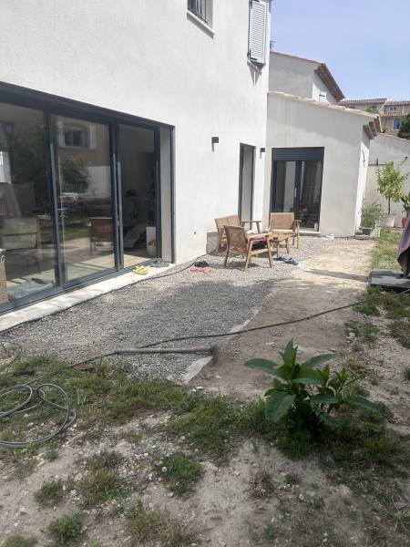 Devant de maison avant aménagement avec dalle en béton et gazon synthétique